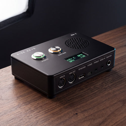 The Rise Keys RK-1 in Stage Black on a walnut desk, its ASSIST and SUSTAIN rings lit